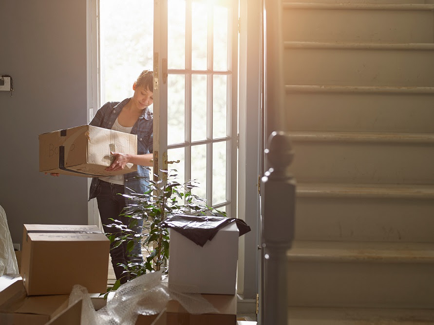 image of new homeowner moving carrying box into her new home